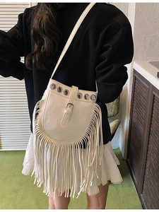 White boho fringe shoulder bucket bag with metallic grommets and tassel details