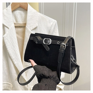 Détail du sac bandoulière en daim noir avec boucle argentée et lanière de cuir lisse