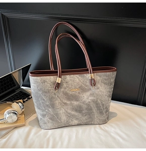 Detail of grey marble texture tote bag with brown handles and golden metal logo