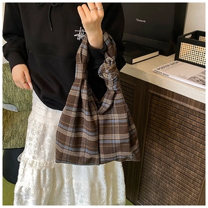 Close-up of brown plaid tote bag with light blue accents and creative knotted handle detail