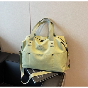 Detail of light green canvas fitness bag with brand logo and reinforced straps
