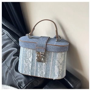 Detailed close-up of retro denim box bag featuring white lace trim and brown leather handles