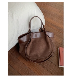 Detail of a brown tote bag featuring mixed textures of smooth leather and soft suede