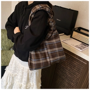 Detail view of the coffee brown checkered tote bag worn over the shoulder by a model