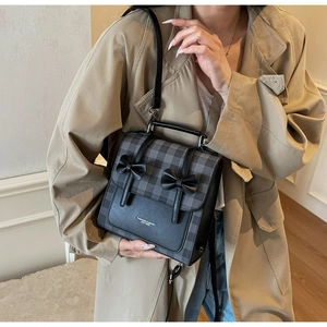 Dettaglio della borsa vintage a quadri con fiocchi neri e elegante manico in pelle