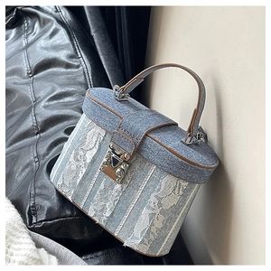 Detail of blue denim bucket bag with white lace floral patches and brown leather handle