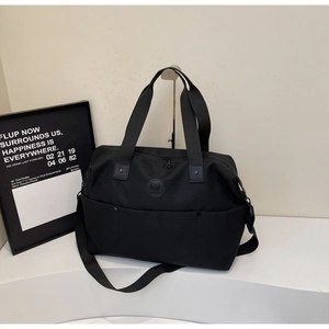 Close-up of black gym bag with durable nylon handles, logo detail and shoulder strap