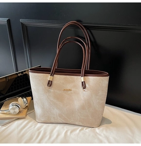 Detail of premium beige velvet tote bag with gold logo and long brown leather handles