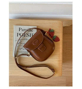 Detailed top view of a brown vintage saddle bag with cute red strawberry charms
