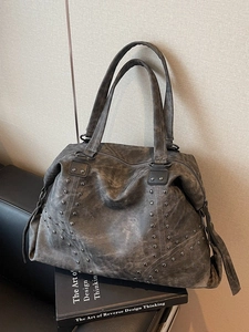 Retro grey oversized tote bag with rivets and vintage PU leather on a designer sofa