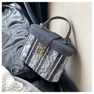 Detail of blue denim bucket bag with white lace floral overlay and brown leather handle