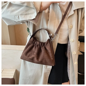 Détail du sac nuage froncé en daim marron foncé porté avec un trench-coat beige