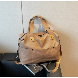 Detailed view of khaki canvas duffel bag featuring front pockets and sturdy handles
