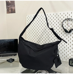 Detail of black nylon dumpling bag with adjustable strap and small side pouch attachment
