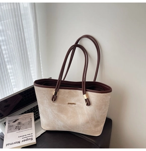 Detail of a large cream suede tote bag with brown straps and golden metal hardware details