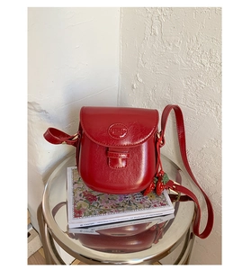 Detail of red vintage saddle bag with strawberry charms on a minimalist background