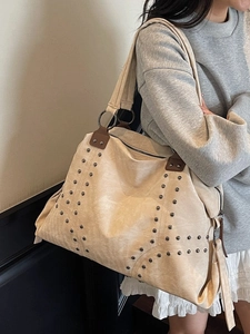 Chic beige canvas rivet tote bag with punk studs shown worn on a model's shoulder