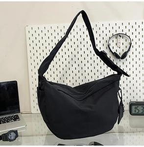 Detail of black nylon crescent bag with adjustable wide strap and mini coin purse pendant