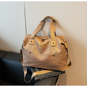 Detail view of khaki canvas duffel bag with reinforced handles and adjustable strap