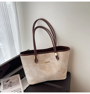 Detailed close-up of cream textured tote bag with dark brown leather trim and metallic logo
