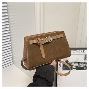 Détail du sac bandoulière vintage en daim avec boucle décorative et garniture en cuir