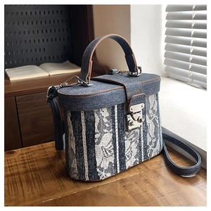 Detailed shot of retro box bucket bag with blue denim, white lace and brown leather trim