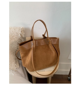 Close-up of the brown tote bag featuring suede texture and smooth leather handle details