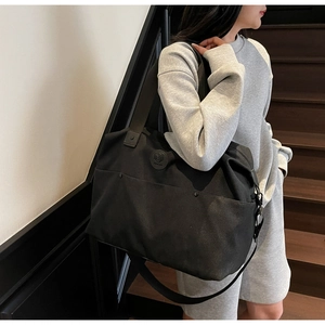 Close-up of black large capacity canvas duffel bag with leather logo and sturdy handles