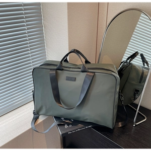 Detailed close-up of army green waterproof nylon travel bag with black woven handles
