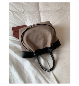 Detail of contrast stitch tote bag with khaki suede body and black leather handles