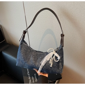 Detail der blauen Jeans-Schultertasche mit Glitzer und Perlen-Spitzen-Bogen-Accessoire