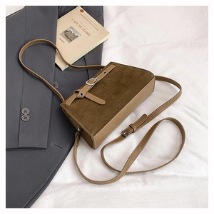 Vue détaillée d'un sac bandoulière vintage en daim marron sur un tissu blanc drapé