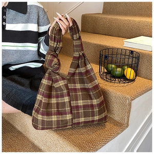Detailed view of plaid tote bag with knot handle design and soft knit texture finish