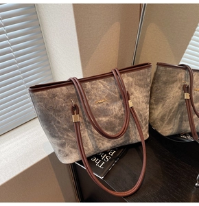 Detailed close-up of grey washed tote bag with brown leather trim and golden hardware
