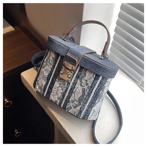 Close-up of a blue denim box bucket bag with white lace detailing and leather handles