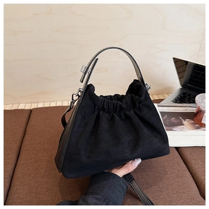 Détail d'un sac plissé en daim noir montrant la texture douce et les finitions argentées