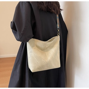 Detail of beige bucket bag with ethnic style floral woven strap and gold metal hooks