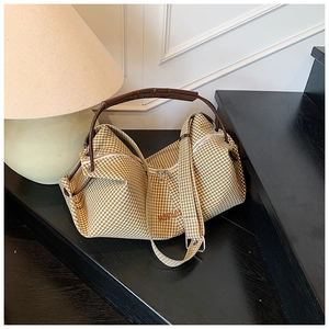 Detail of vintage plaid tote bag with brown leather handle and MOONSS logo on dark stairs