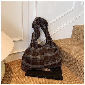 Detail of vintage plaid tote bag featuring twisted knot handle and tweed fabric texture