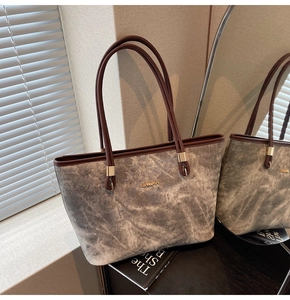Detail of grey marble textured tote bag with golden logo and dark brown handles