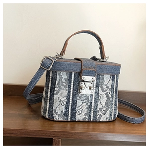 Detail view of retro denim bucket bag with white floral lace and brown leather trim