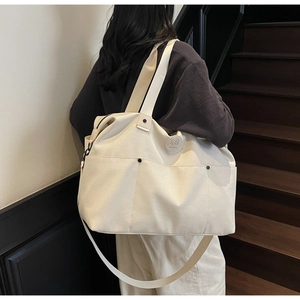 Detailed side view of off-white canvas duffel bag with multiple front pockets and straps