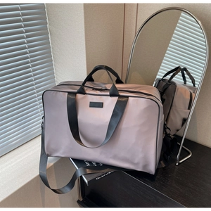 Detail of dusty pink nylon travel bag with black handles and adjustable shoulder strap