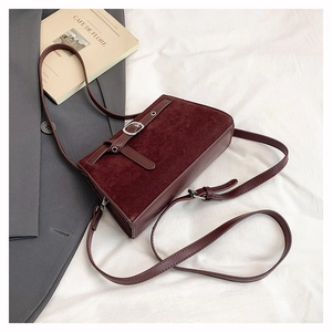 Détail du sac bandoulière bordeaux en daim mat avec boucle argentée élégante