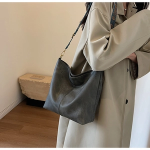 Detail of vintage grey bucket bag with a patterned woven shoulder strap on a trench coat