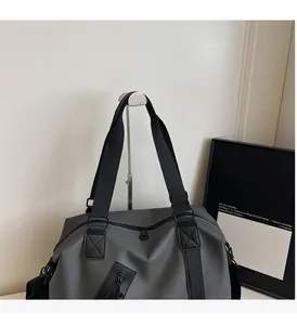 Detail of grey travel bag featuring reinforced black straps and metallic zippers