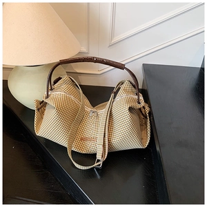 Detail of checkered shoulder bag with Movnost embroidery and brown leather handle