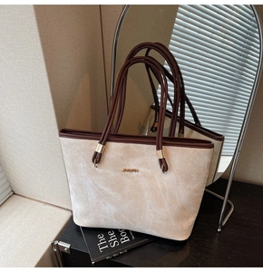 Detail of a minimalist tote bag featuring cream suede fabric and dark brown leather accents