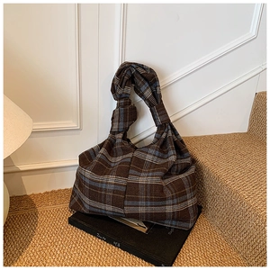 Detail of vintage plaid tote bag with thick fabric texture and knot handle design