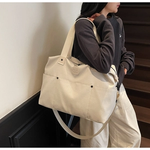 Large off-white canvas sports bag with adjustable strap shown on model in casual setting